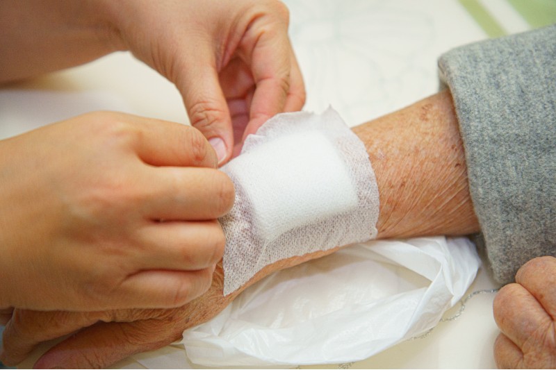 Nurse applying bandage to elderly patient